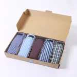 5 gefaltne klassische Boxershorts in verschiedenen Farben und Mustern sind in einer geöffneten Verpackung.